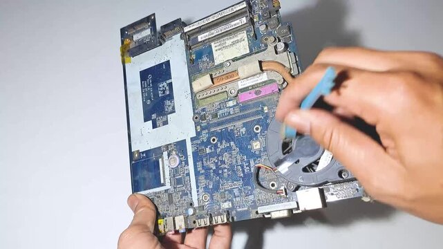 Cleaning dusty laptop CPU cooling fan on mainboard with brush tool concept of computer hardware repair service laptop maintenance dust removal component fixing electronic technical support