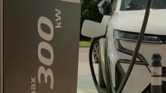 An electric car is connected to a charging station that provides fast charging. The station is located in an outdoor area and is ready for use by drivers.