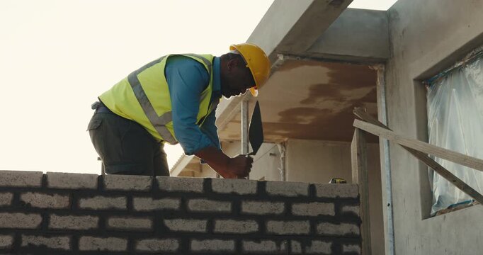 Brick wall, building and civil engineering with black man in neighborhood for property development. Construction, home and process with builder on worksite for addition, improvement or security