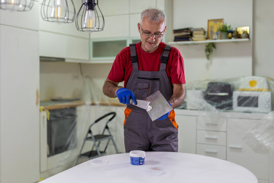 Senior man applying putty during kitchen renovation