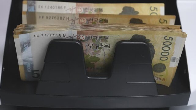 Close-up Fixed Shot of Money Counting Machine Counting 100 Crisp 50,000 Won Banknotes (Cash, Banking, Finance)