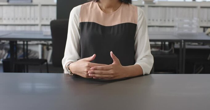 Close up of people talking to the camera, sitting at desk, woman with clasped hands in business atti