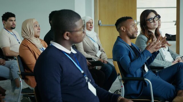 A diverse group of attentive professionals and business people are actively participating in a conference. They are seated, engaged, and focused on learning and networking at a professional event.