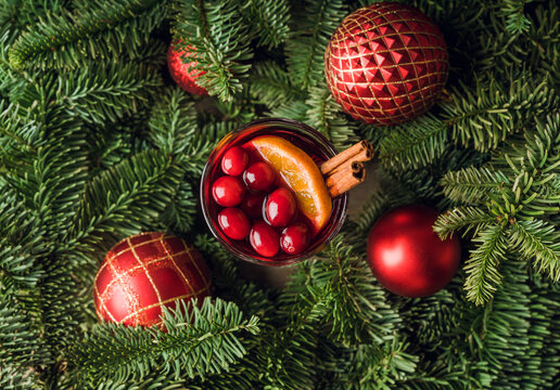 Mulled wine with orange, cranberry and cinnamon in fir forest setting. Selective focus.