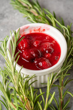 Homemade cranberry sauce in white ceramic bowl on concrete background