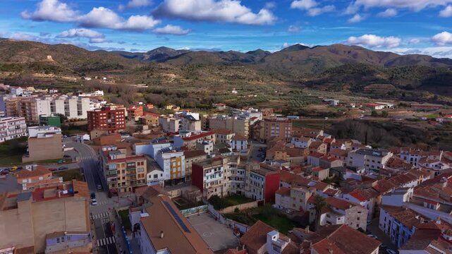 Chelva traditional Spanish village nestled among green mountains in Valencia region, featuring terracotta rooftops, colorful facades and blue cloudy sky