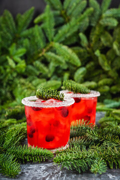 Red christmas cocktail with cranberry juice on the fir branches background. Christmas mood. Selective focus. 