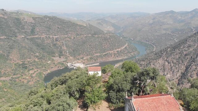 Aerial, drone shot flying forward over the Douro River, revealing Valeira Dam and S&atilde;o Salvador do Mundo Hermitage, Portugal