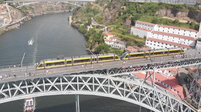 Aerial, drone shot tracking a tram along the upper deck of Dom Luis I Bridge in a semicircular movement, Porto, Portugal