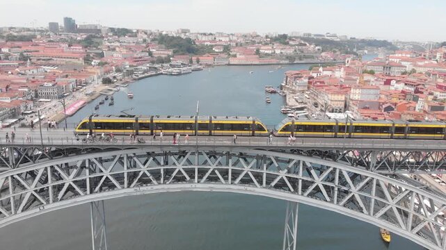 Aerial: Drone tracking tram moving across the upper deck of Dom Luis I Bridge in Porto, Portugal