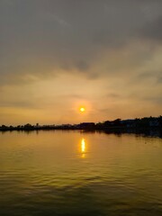 Fototapeta premium Serene golden sunset over calm lake waters reflecting the warm evening sun and clouds with twilight