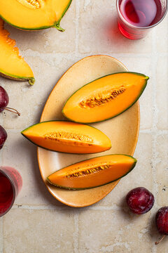 tranches de melon fra&icirc;ches sur une table, prunes et jus de fruits frais