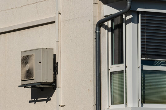 Air conditioning unit mounted on the wall near a window