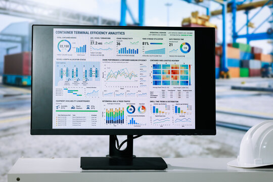 Computer monitor container terminal efficiency analytics dashboard in a busy cargo port, with cranes, shipping containers and safety helmet in the background.