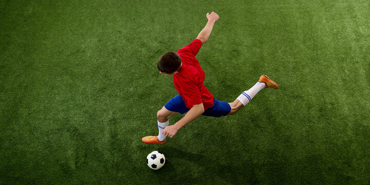 Overhead view of player dribbling diagonally across grass. Concept of ball progression, directional movement, individual attack and tactical field positioning.