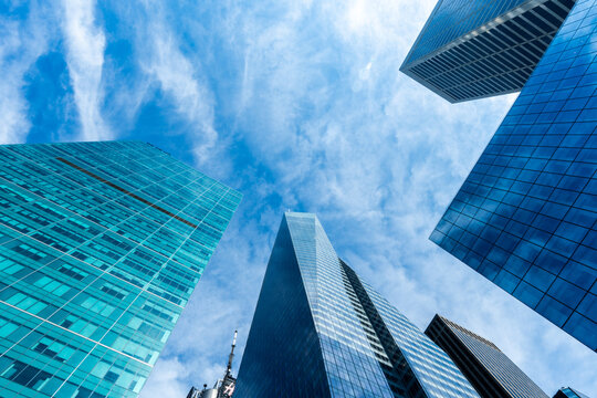 Modern skyscrapers and glass office buildings in business district, captured from low angle perspective with blue sky, symbolizing architecture, urban growth, corporate success, and city development.