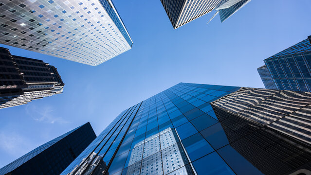 Modern skyscrapers and glass office buildings in business district, captured from low angle perspective with blue sky, symbolizing architecture, urban growth, corporate success, and city development.