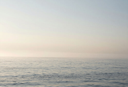 A serene ocean scene with a layer of soft mist hovering just above the water, copy space