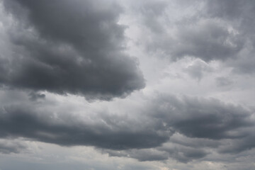 Fototapeta premium Stratocumulus Dramatic Dark Storm Clouds with Sunlight Breaking Through Over Blue Sky