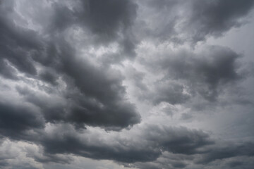 Fototapeta premium Stratocumulus Dramatic Dark Storm Clouds with Sunlight Breaking Through Over Blue Sky