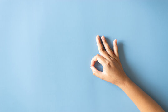 Hand showing OK sign gesture on blue background