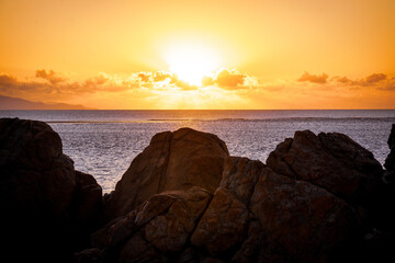 Obraz premium Aerial video along a tropical beach at dawn with golden sunrise over rocks Mackay Queensland Australia