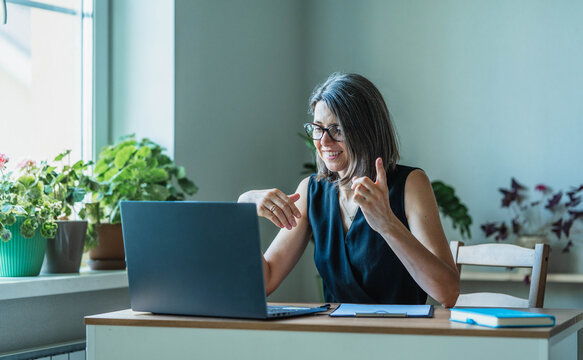 Smiling businesswoman gestures during a video conference at home