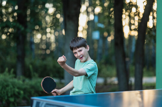 Happy boy celebrates winning a table tennis match in the park
