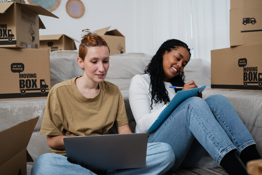Couple planning home move together with laptop and checklist in living room