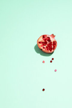 A fresh half pomegranate rests on a green background