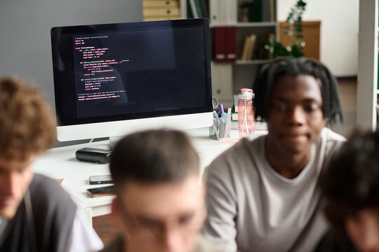 A computer screen shows code in front of blurred students in class