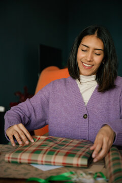 Smiling woman wrapping a Christmas present indoors