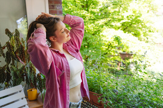 Woman relaxes on a tiny green balcony enjoying her morning routine