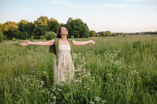 Smiling mature woman standing in a meadow with arms outstretched