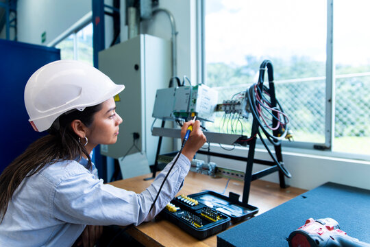 Woman engineer repairs electronic module at indoor workshop