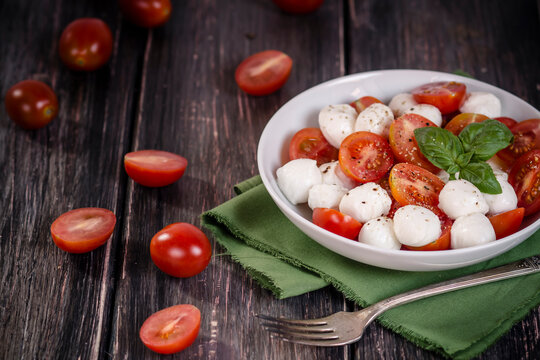 Caprese Salad in plate on wooden table, studio shot