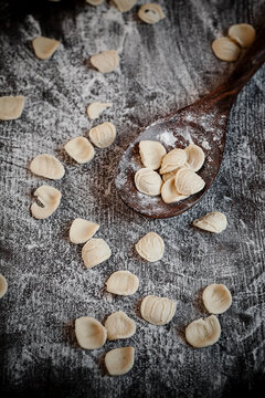 Orecchiette on wooden spoon and wooden table with flour