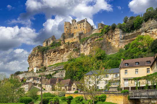 View of Beynac-et-Cazenac with castle on top of cliff, France. Medieval stone village under partly cloudy sky