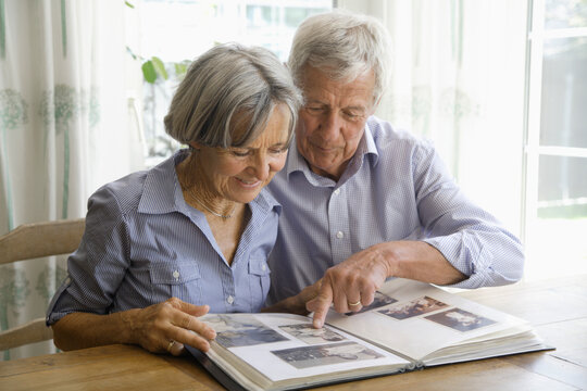 Germany, Bavaria, Senior couple with photo album, smiling