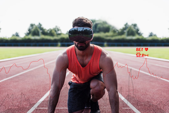 Athlete in starting position on tartan track wearing VR glasses surrounded by data