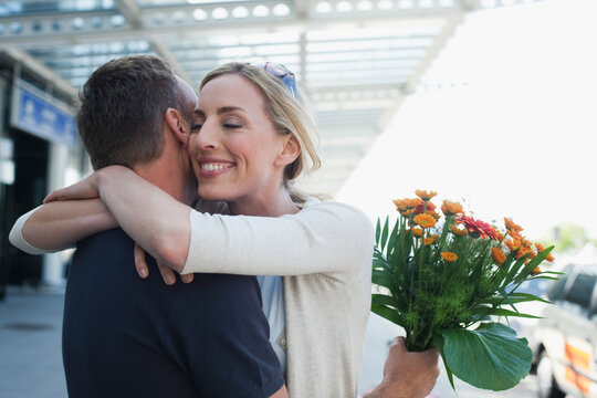Germany, Leipzig-Halle, Airport, Couple embracing, Man holding flowers