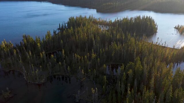 4K aerial drone footage of Summit Lake near Diamond Peak Wilderness, Oregon, USA, at sunset on a clear late summer evening, surrounded by dense evergreen forest in the Cascade Mountains