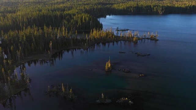 4K aerial drone footage of Summit Lake near Diamond Peak Wilderness, Oregon, USA, at sunset on a clear late summer evening, surrounded by dense evergreen forest in the Cascade Mountains
