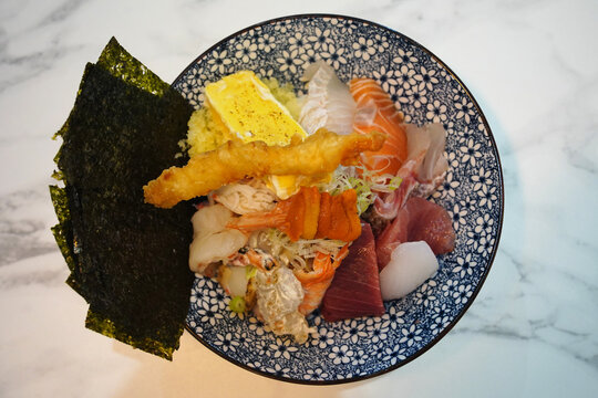 Japanese kaisendon seafood rice bowl topped with salmon, tuna, shrimp tempura, and tamago