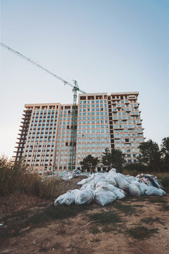 Construction progress on a modern urban building surrounded by greenery and debris