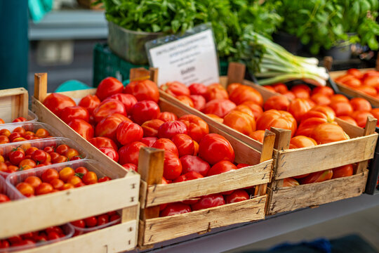 Fresh Red Tomatoes in Wooden Crates at Produce Market. Fresh red tomatoes displayed in wooden crates at an outdoor produce market.