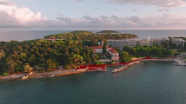 Aerial view of Sveti Andrija island featuring the historic monastery building and hotel surrounded by lush pine forests and the Adriatic Sea in Rovinj, Istria County, Croatia.