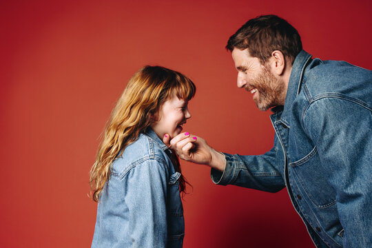 Father bends down to talk compassionately with daughter in studio portrait