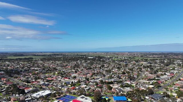 Aerial of residential housing, local school sports grounds, and outer-suburban urban fringe stretching toward Port Phillip Bay in Werribee, Melbourne, Victoria, Australia. Established neighborhood