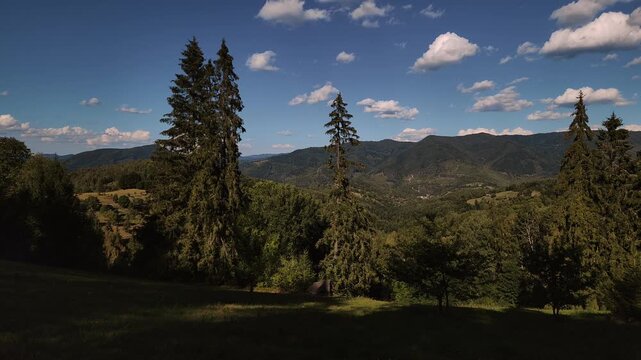 footage featuring a wide 30 fps panoramic shot of a vast green mountain valley under a deep blue sky with scattered white fluffy clouds. Ideal for travel documentaries, nature projects,